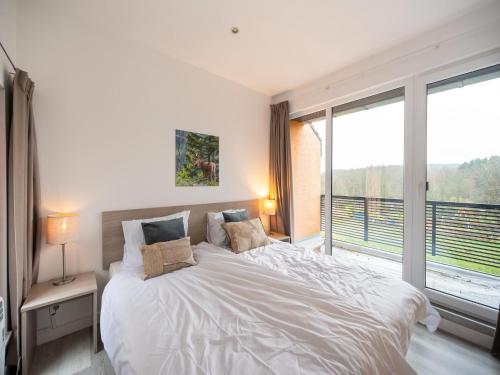a bedroom with a large white bed and a large window at Hambachtal forest hideaway boutique resort in Oberhambach