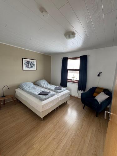 a bedroom with a bed and a blue chair at Guesthouse Myrkholt II in Tungufell