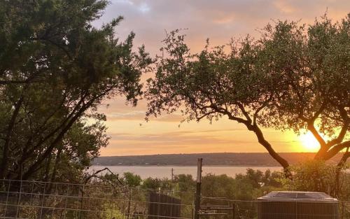a sunset over the water with trees and a fence at Ranchette Apartment- beach access small lake view in Buchanan Dam