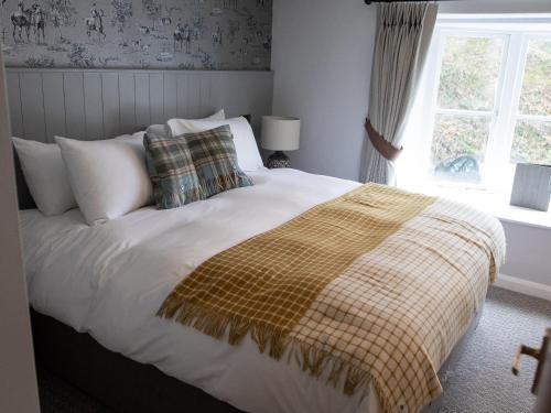a bedroom with a bed with a blanket and a window at The Exeter Inn in Bampton