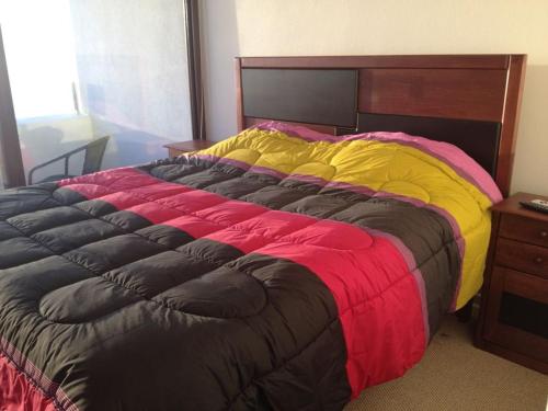 sypialnia z dużym łóżkiem z czerwonym i żółtym kocem w obiekcie Departamento Coquimbo Vista Al Mar w mieście Coquimbo