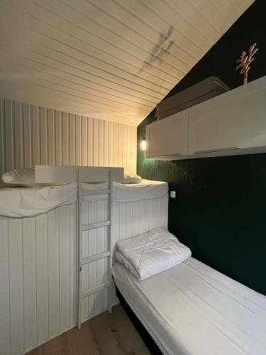 two white bunk beds in a room with a green wall at Chalet de la fée Marion et Alice in Virton