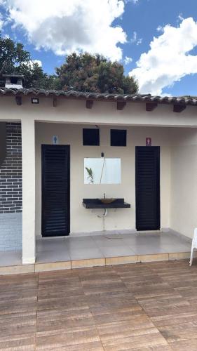 a white building with black doors and a bench on it at Recanto do boto in Anápolis