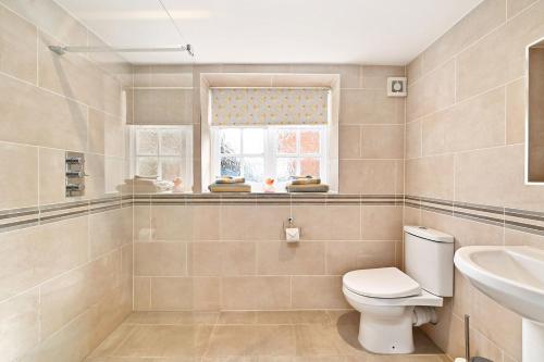 a bathroom with a toilet and a sink and a window at Plum Pudding Stables by Bloom Stays in Faversham
