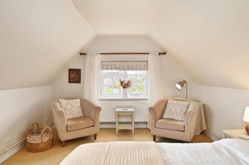 a attic bedroom with two chairs and a window at Plum Pudding Stables by Bloom Stays in Faversham
