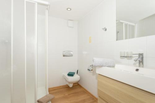 a white bathroom with a toilet and a sink at Penzion Quest in Loket