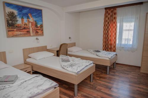 a room with three beds and a painting on the wall at Hotel Holy Miracle in Međugorje