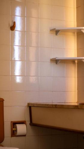 a tiled bathroom with a toilet and a shelf at Maktub Hotel Itu in Itu