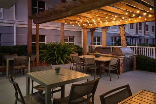 an outdoor patio with tables and chairs and a grill at Homewood Suites by Hilton Daytona Beach Speedway-Airport in Daytona Beach