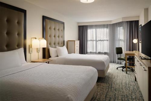 a hotel room with two beds and a desk at Homewood Suites by Hilton Daytona Beach Speedway-Airport in Daytona Beach