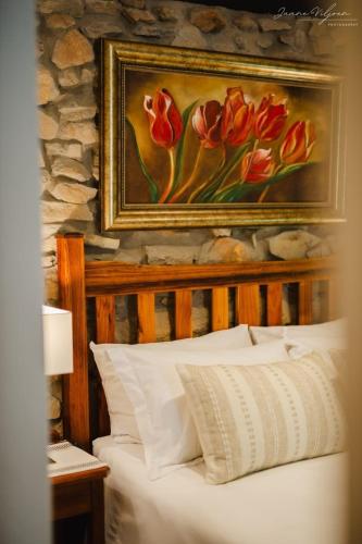 a painting of red tulips is above a bed at Uitkyk Kliphuisie in Uniondale
