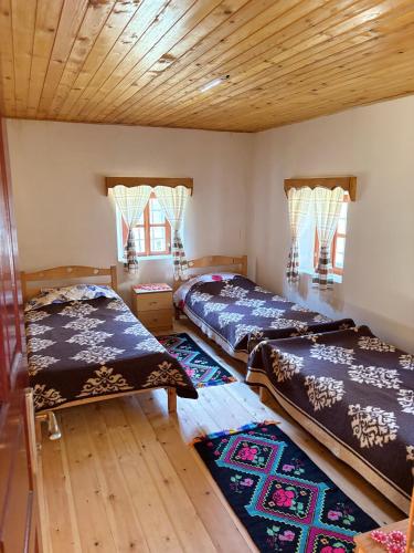 two beds in a room with wooden floors and windows at Guest House Prebibaj in Curraj i Epërm