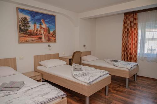 drei Betten in einem Zimmer mit einem Gemälde an der Wand in der Unterkunft Hotel Barbaric in Međugorje