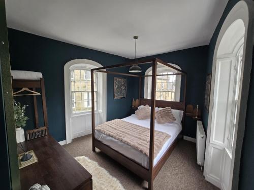 a bedroom with a canopy bed and blue walls at The Counting House in Alnwick