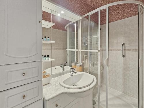 a white bathroom with a shower and a sink at Sérénité vue mer in Courseulles-sur-Mer