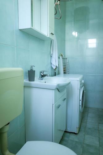 a bathroom with a sink and a washing machine at Apartments LungoMare in Tivat