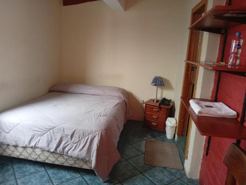 a small bedroom with a bed and a night stand at Hospedaje Las Garzas in Ibarra