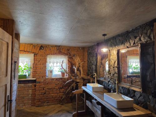 a bathroom with two sinks and a brick wall at Leśna Ostoja in Goworów