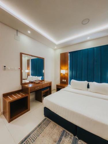 a bedroom with a bed and a desk and a mirror at شقق أونيسن للشقق المخدومة Onsen Serviced Apartments in Buraydah