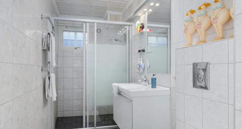 a white bathroom with a shower and a sink at Spacious villa with heated pool and stunning view in Tokenes
