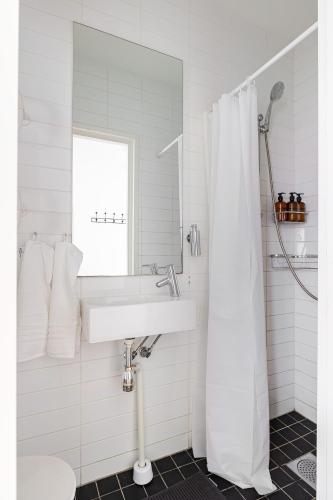 a white bathroom with a sink and a mirror at Chic 2-Bedroom apartment on Lidingö in Lidingö