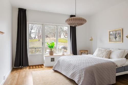 a white bedroom with a bed and a window at Chic 2-Bedroom apartment on Lidingö in Lidingö