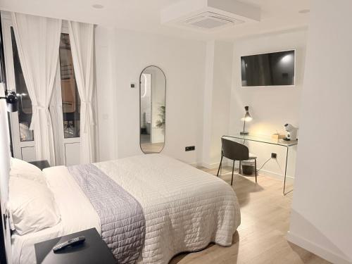 a white bedroom with a bed and a desk at Hospedaje C-17 in Segovia