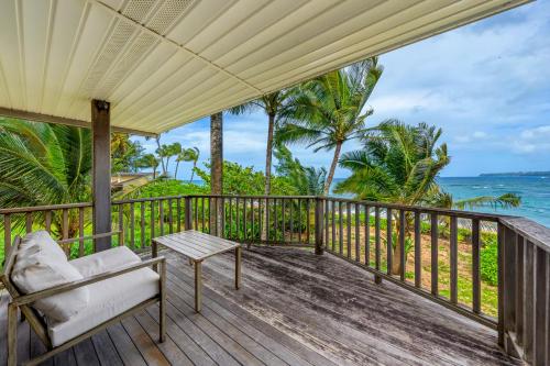 a porch with a chair and a table and the ocean at Hale Kepuhi in Hanalei