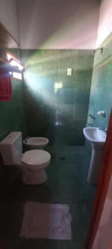 a green bathroom with a toilet and a sink at Cabañas Donato in Colonia Benítez