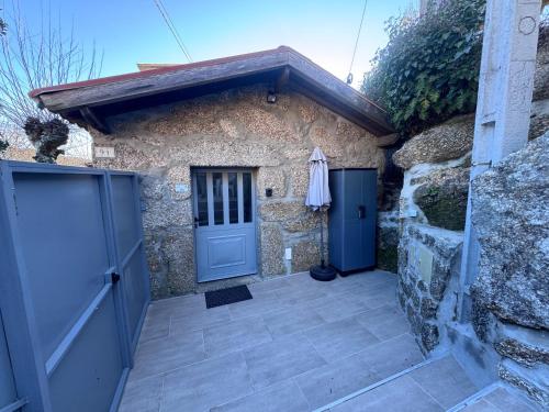 a stone house with a blue door and a stone wall at Gerês Natura in Valdosende
