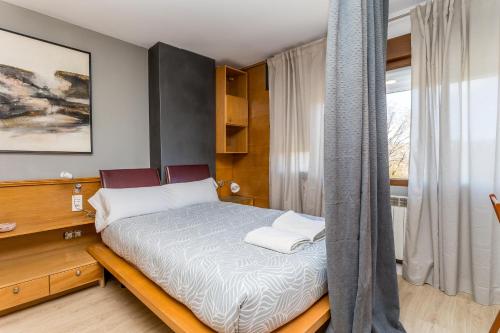 a small bedroom with a bed and a window at BaruHaus triplex piscina y parking in Villamañán