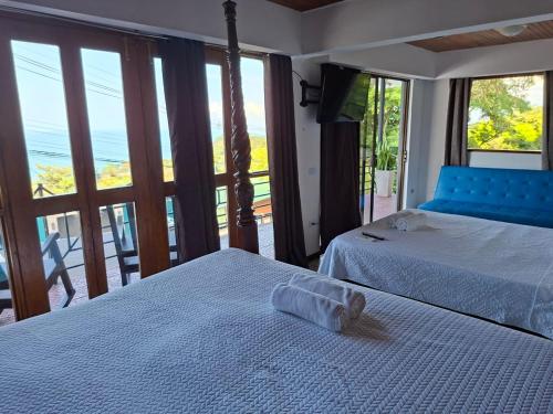 two beds in a room with a view of the ocean at Hotel Manuel Antonio Beracha in Quepos