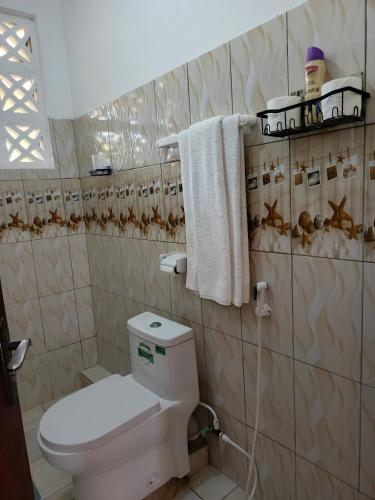 a bathroom with a toilet and towels on a wall at Catwalk Factory Apartment in Ukunda