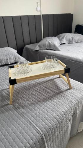 a tray with two glasses on top of a bed at Costa Suite Enseada in Guarujá