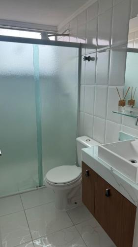 a bathroom with a toilet and a shower and a sink at Costa Suite Enseada in Guarujá