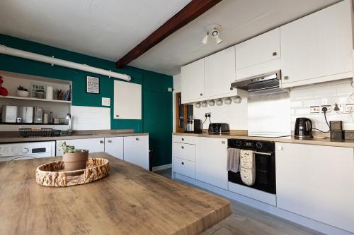 a kitchen with white cabinets and a wooden table at OLD WEAVERS COTTAGE - Charming Historic Weavers Cottage in Holmfirth, West Yorkshire in Holmfirth