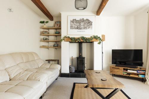 a living room with a white couch and a television at OLD WEAVERS COTTAGE - Charming Historic Weavers Cottage in Holmfirth, West Yorkshire in Holmfirth