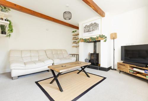 a living room with a white couch and a tv at OLD WEAVERS COTTAGE - Charming Historic Weavers Cottage in Holmfirth, West Yorkshire in Holmfirth