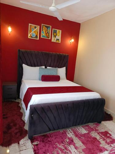 a bedroom with a large bed with red walls at Catwalk Factory Apartment in Ukunda