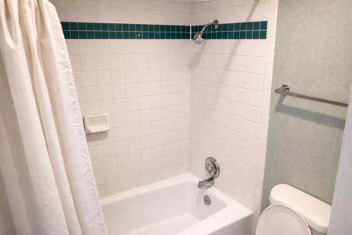 a bathroom with a white tub and a toilet at Tree Inn & Suites Albuquerque in Albuquerque