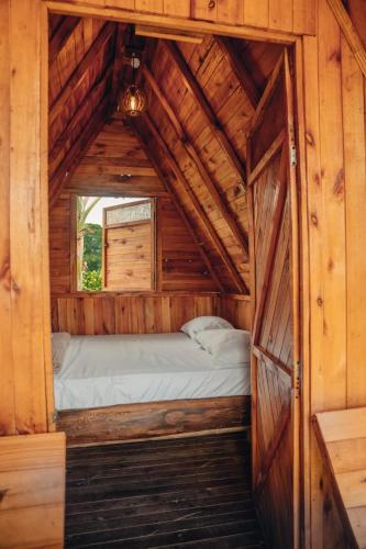 a bed in a wooden cabin with a window at Kindia Park Hotel in La Esmeralda