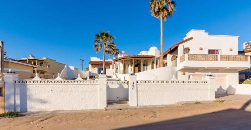 a white fence in front of a house with palm trees at Recently Renovated Oceanview Home Casa Hebe in Puerto Peñasco