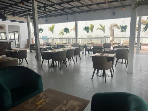 a restaurant with tables and chairs and palm trees at Hôtel NGOR ALMADIES 4 étoiles in Dakar