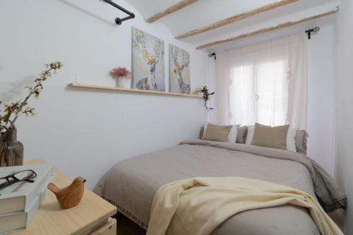 a white bedroom with a bed and a window at Calderona Tiny house in Segorbe