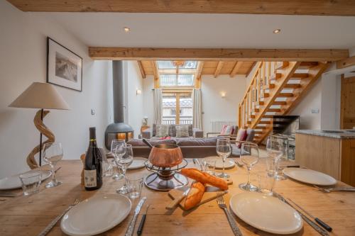 a dining room table with glasses and wine bottles at Apt Clusettes 1-min walk to ski + parking & WiFi - Happy Rentals in Chamonix