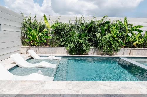 a swimming pool with two white chairs in front of a house at Expansive 7 Bedroom Home Heated Pool & Spa in New Orleans