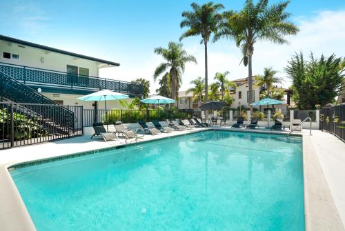 a pool with chairs and umbrellas at a resort at Pacific Crest Hotel Santa Barbara in Santa Barbara