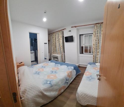 una camera da letto con due letti e una televisione di Perola da Baixa a Lisbona