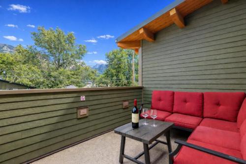 a patio with a red couch and a table with wine glasses at Pyrenees #202 - LEED Gold Certified in Canmore