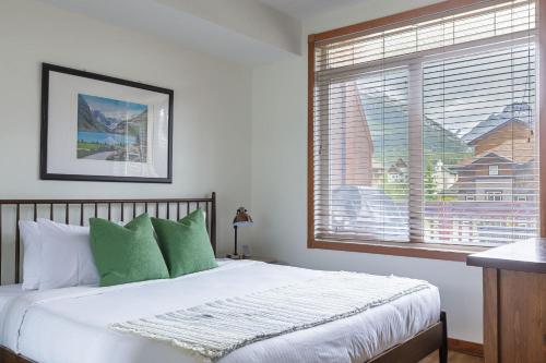 a bedroom with a bed with green pillows and a window at Mountain Paradise at Falcon Crest Lodge in Canmore